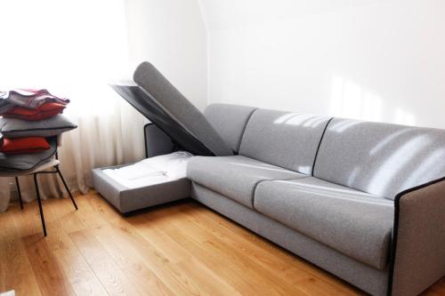 a gray couch in a room with a wooden floor at UrbanKop Vidik Residence in Kopaonik