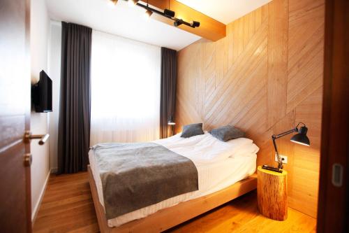 1 dormitorio con 1 cama con pared de madera en UrbanKop Vidik Residence, en Kopaonik