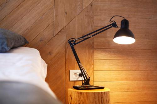 a black lamp sitting on a table next to a bed at UrbanKop Vidik Residence in Kopaonik