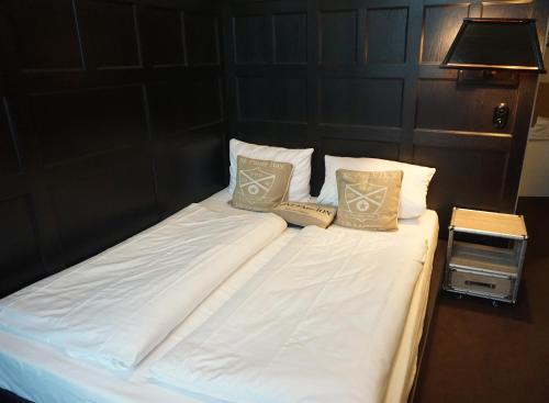 a bed with white sheets and pillows and a lamp at Hotel Bucheneck in Linz am Rhein