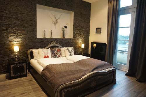 a bedroom with a large bed and a brick wall at Hotel Bucheneck in Linz am Rhein