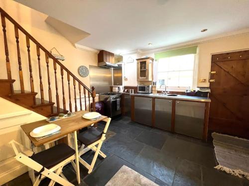 een keuken met een houten tafel en een aanrecht bij Characterful & cosy cottage with large double room in Manningtree