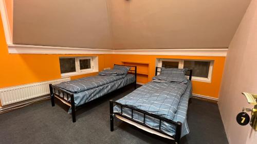 2 camas en una habitación con paredes y ventanas de color naranja en Mexx Hostel, en Baku