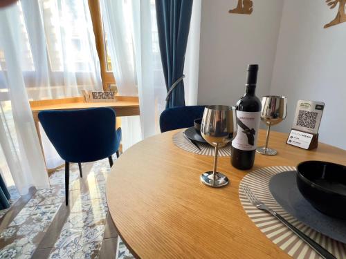 a table with a bottle of wine and two wine glasses at Blue Apartment Pirin Golf & Spa in Bansko