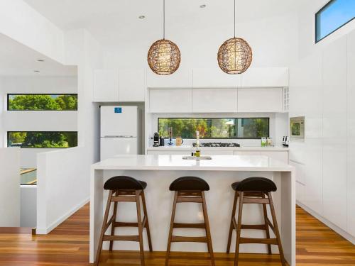 a kitchen with a large white island with two bar stools at Soho Beach House - Apollo Bay in Apollo Bay