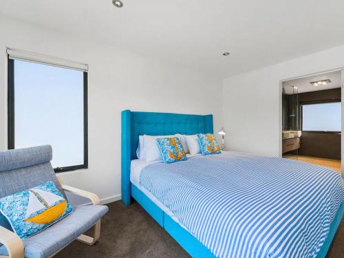 1 dormitorio con 1 cama azul y 1 silla en Soho Beach House - Apollo Bay, en Apollo Bay