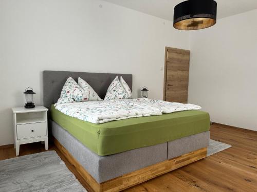 a bedroom with a green bed with a night stand at Stilvoll renovierte Wohnung in Lienz