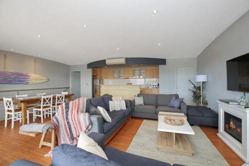 Una sala de estar con un sofá azul y una cocina. en The Beachhouse at The Butter Factory, en Apollo Bay