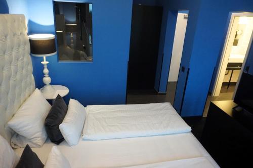 a bedroom with a white bed and a blue wall at Hotel Bucheneck in Linz am Rhein