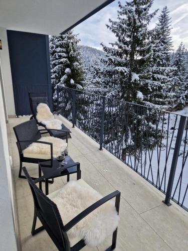 a balcony with chairs and a view of snow covered trees at GO Jahorina by Olympic Gardens in Jahorina