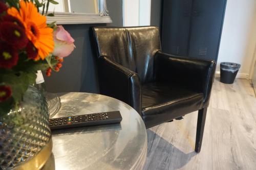 a black leather chair next to a table with a remote control at Hotel Bucheneck in Linz am Rhein