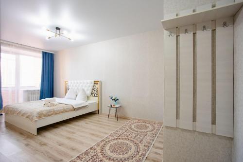a white bedroom with a bed and a rug at 1-ком Тобол Арена, Костанай Плаза, Allur auto, НИШ БЕРЕКЕ in Kostanay