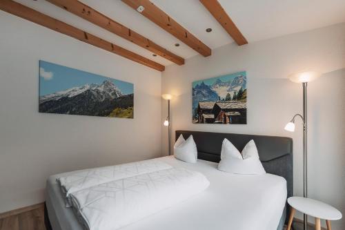 カップルにあるAlp Chalet Appartementの白いベッド1台と壁に2枚の絵が飾られたベッドルーム1室が備わります。