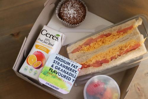 a box of food with a sandwich and a cupcake at The Raz in Harrismith