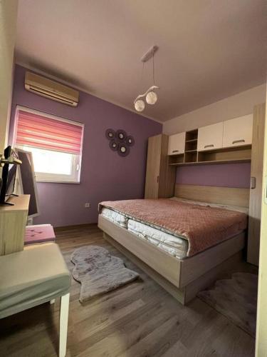 a bedroom with a bed and a purple wall at Apartman Centar in Tribunj