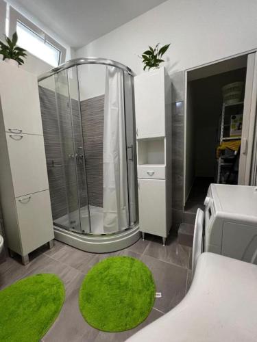 a bathroom with a shower and a green rug at Apartman Centar in Tribunj