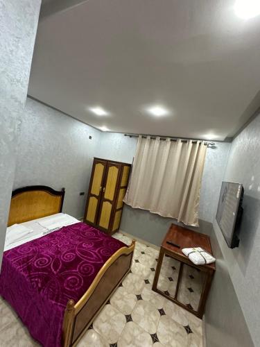 een slaapkamer met een paars bed en een tafel bij HOTEL NOSTRESS in Khenifra