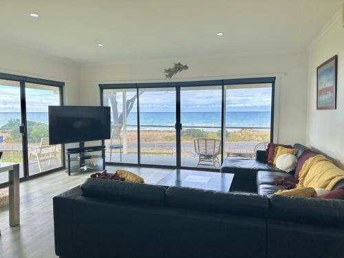 sala de estar con sofá y TV de pantalla plana en Seaspray Beach House - Pet Friendly - 50m to Beach, en Apollo Bay