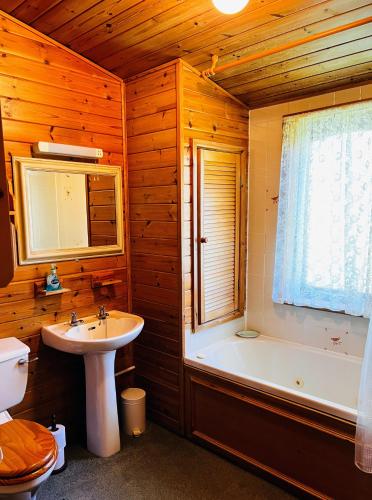 y baño con lavabo, bañera y aseo. en Secluded Rustic Cabin - A Digital Detox Paradise. en York