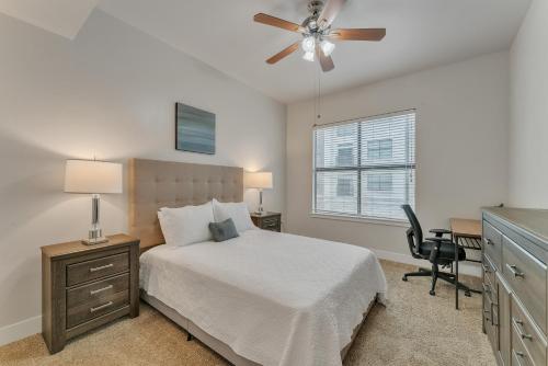 een slaapkamer met een bed, een plafondventilator en een bureau bij Cozy 1 Bedroom Suite, Pool, Gym, Parking Cs in Dallas