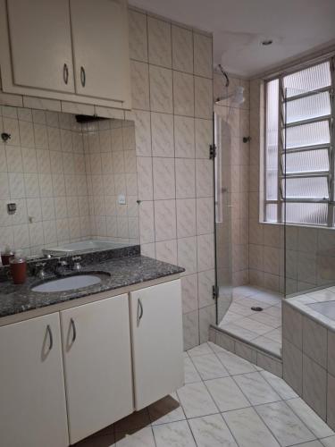 a bathroom with a shower and a sink and a tub at Pé na areia Gonzaguinha São Vicente in São Vicente