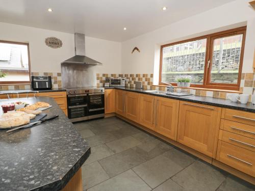 a large kitchen with wooden cabinets and a black counter top at Y Tylwyth in Blaenau-Ffestiniog