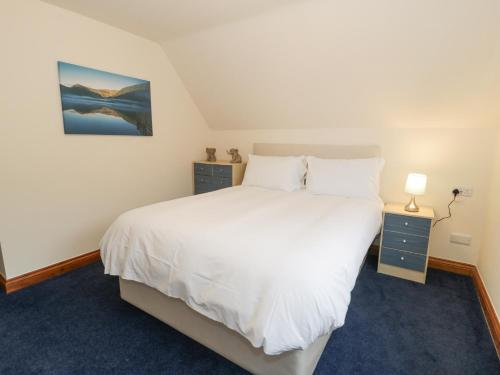 a bedroom with a large white bed and two night stands at Y Tylwyth in Blaenau-Ffestiniog