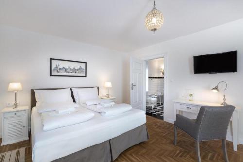 a bedroom with a white bed with a desk and a chair at Pałacyk Szklarska in Piechowice
