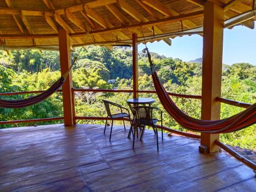a porch with a hammock and a table and chairs at Casa Magica in Minca