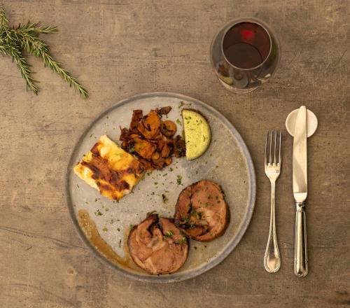 a plate of food with meat and a slice of pizza at Logis Hôtel La Ferme de Flaran in Maignaut