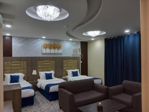 a hotel room with two beds and a couch at لانا العلا شقق مفروشة Lana Alula in AlUla