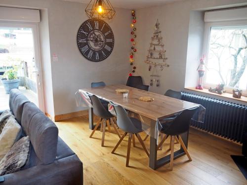 a dining room table with chairs and a clock on the wall at Appartement Maison Vosgienne La Bresse Centre in La Bresse