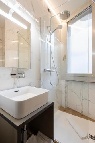 a white bathroom with a sink and a shower at London Hotel in Milan