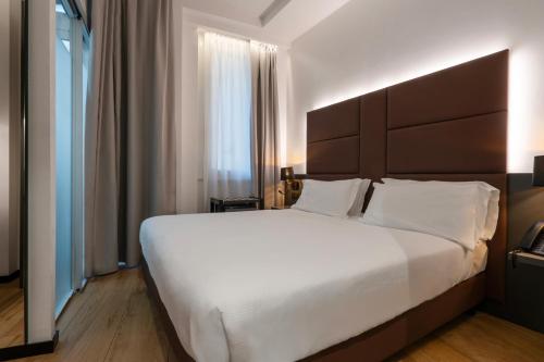 a bedroom with a large white bed and a window at London Hotel in Milan