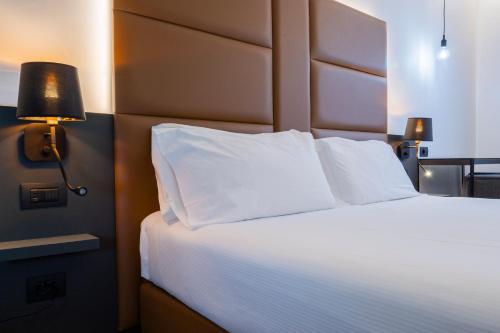 a bedroom with a large bed with white pillows at London Hotel in Milan