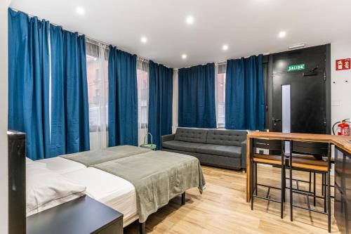 ein Schlafzimmer mit einem Bett und einem Sofa sowie blauen Vorhängen in der Unterkunft VR LATINA APARTMENTS in Madrid