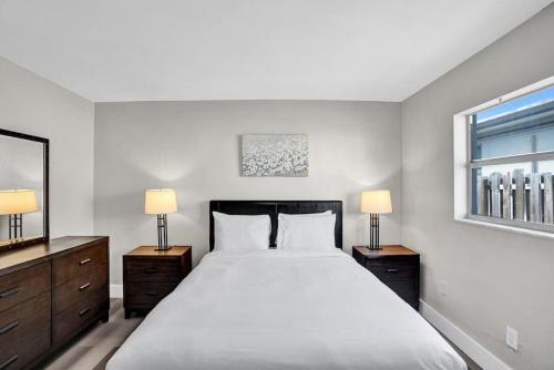 a white bedroom with a large bed with two lamps at Pionciana Getaway 1BR Apartment Near FLL Airport in Fort Lauderdale