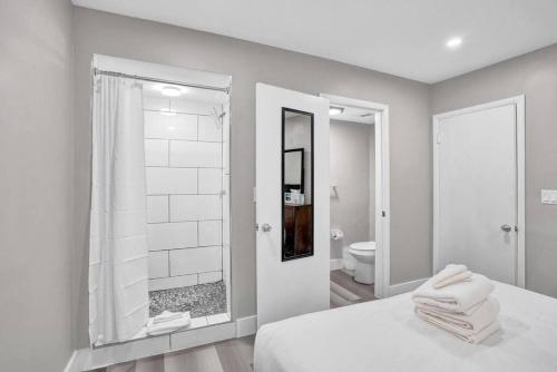 a white bedroom with a bathroom with a shower at Pionciana Getaway 2BR Apartment Near FLL Airport in Fort Lauderdale