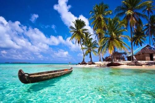 un barco en el agua en una playa con palmeras en Hotel Pension Corona, en Panamá
