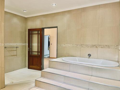 a bathroom with a tub and a walk in shower at The Stella Guest House & Spa in Ermelo