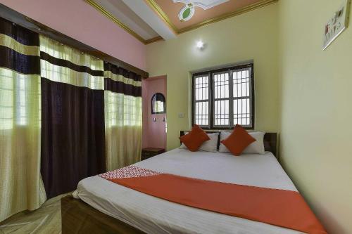 a bedroom with a large bed with orange pillows at OYO Flagship Ashoka Guest House in Bihta