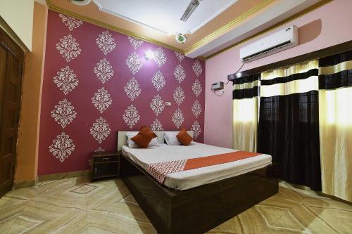 1 dormitorio con cama y pared púrpura en OYO Flagship Ashoka Guest House en Bihta