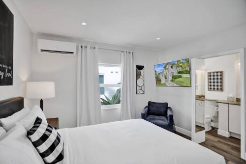 Beach Isles Modern Studio Apartment in Fort Lauderdale في فورت لاودردال: غرفة نوم بسرير أبيض وكرسي أزرق