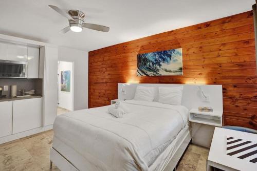 a bedroom with a white bed with a wooden wall at Waves Beach Town Cozy Studio Apartment in Pompano Beach