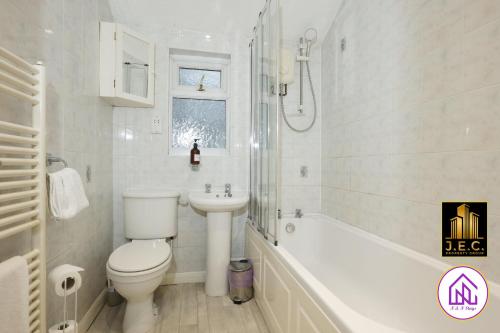 a white bathroom with a toilet and a sink at Clodien House, Great Location, Free Parking in Cardiff