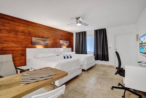 1 dormitorio con 2 camas y pared de madera en Waves Beach Town Spacious Studio Apartment For 4 People en Pompano Beach