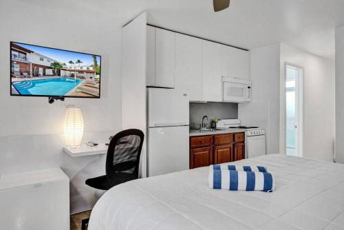 a white bedroom with a bed and a kitchen at Waves Beach Town Cozy Studio Apartment in Pompano Beach