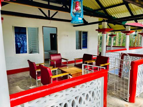 a patio with red chairs and a table on a building at Fairy Hills ( Cottage & Park ) in Sreemangal