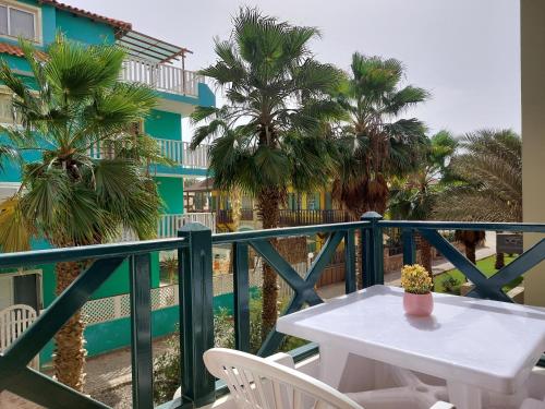 a white table and chairs on a balcony with palm trees at Branco Sea Holiday Apartments in Santa Maria