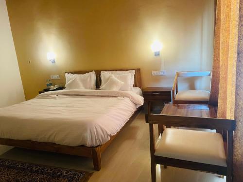 a bedroom with a bed and a desk and a chair at The Deerfield Cottages in Rāmnagar